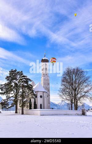 Hot air balloon over the Sankt Coloman pilgrimage church near Schwangau in winter, Allgäu, Swabia, Bavaria, Germany, Europe Stock Photo