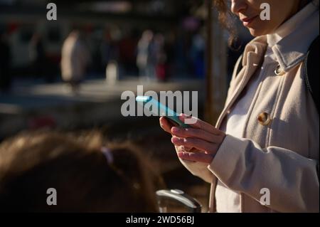 Close-up female passenger checking her online ticket on mobile app on her smartphone, waiting for the train in the railway station. People. Wireless t Stock Photo