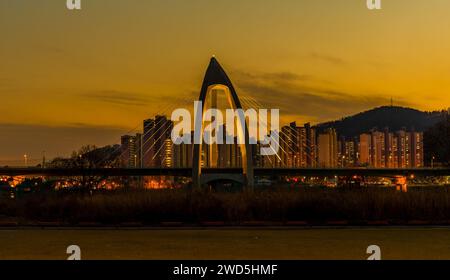 Night view of concrete bridge with triangular arch over a river with ...