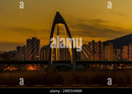 Night view of concrete bridge with triangular arch over a river with ...