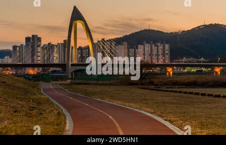Night view of concrete bridge with triangular arch over a river with ...