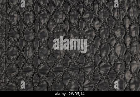 A pattern on a black leather surface. Black leather texture background close-up. Stock Photo