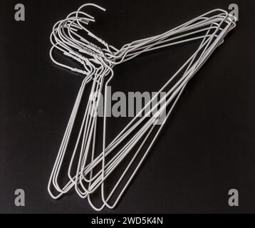 Stack of white wire clothes hangers laying on black background, South Korea Stock Photo