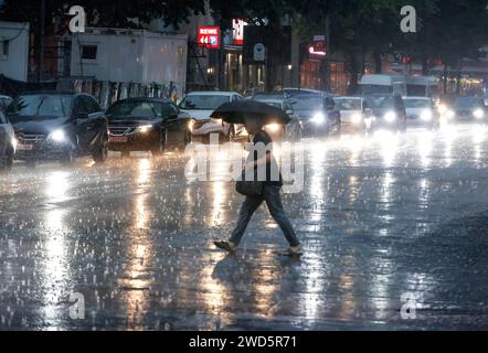 People try to protect themselves from the rain on Potsdamer Strasse. After weeks of heat, the first heavy rain brought cooling, Berlin, 15.08.2022 Stock Photo