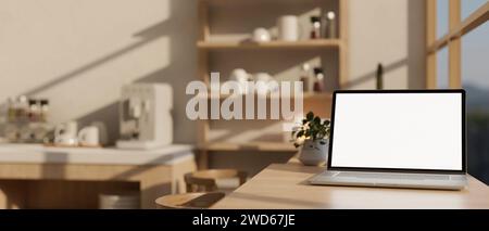 A white-screen laptop computer mockup on a dining table against the window in a modern kitchen or office break room on a sunny day. 3d render, 3d illu Stock Photo