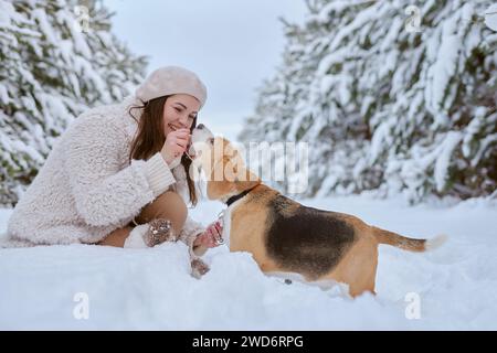 girl in winter clothes plays with Beagle dog in winter in the snow, winter holiday concept Stock Photo