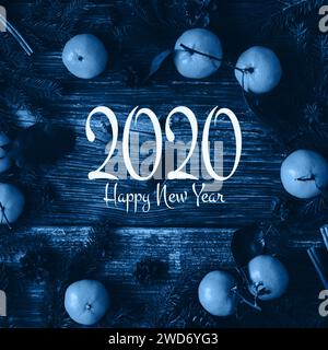 Classic blue main color trend of the Year 2020. congratulatory inscription 2020 Happy New Year on a wooden background with framed with tangerines and Stock Photo
