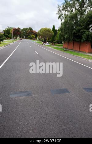A suburban side street leading off through a small park towards houses Stock Photo