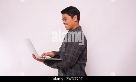 Asian student typing on a laptop against white background Stock Photo