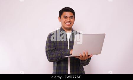 Asian student standing on studio while using laptop against white background Stock Photo