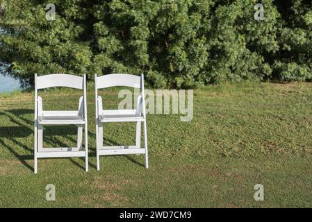 The two chairs placed on a green lawn set up for an outdoor wedding ceremony Stock Photo