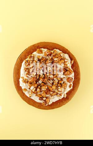 sponge cake with cream and nuts on a yellow background Stock Photo