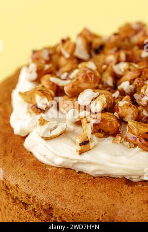 sponge cake with cream and nuts on a yellow background Stock Photo
