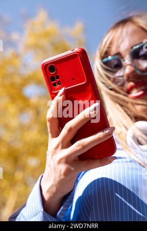 Vertical shot Young happy caucasian woman surfing the internet with outdoor smart mobile app. Stock Photo