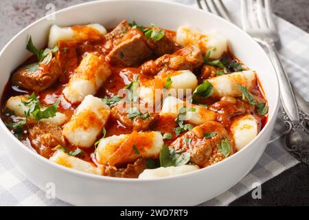 Potato dumplings or kopytka is made with cooked mashed potatoes served meat gravy close-up in a plate on the table. Horizontal Stock Photo