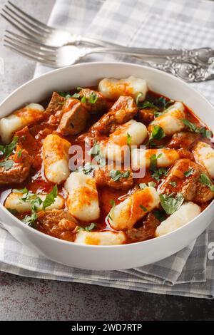 Boiled potato dumplings Kopytka with meat gravy close-up in a plate on the table. Vertical Stock Photo