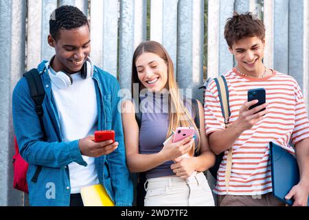 Multiracial Group Of Smiling Students Browsing Smartphone App Outdoors. Stock Photo