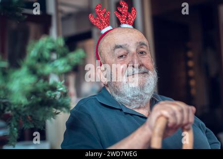 elderly man with reindeer ears holding a walking stick Stock Photo