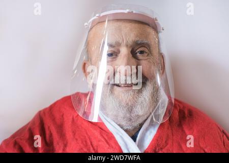 elderly man wearing a protective visor and Santa Claus suit Stock Photo