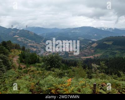 scenic view of a valley with a small town nestled among green mountains under an overcast sky Stock Photo