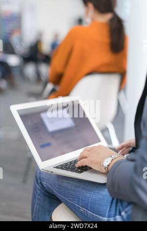 woman using a laptop taking notes during a seminar presentation Stock Photo