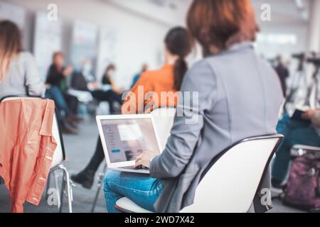 woman sitting at conference meeting taking notes on laptop Stock Photo