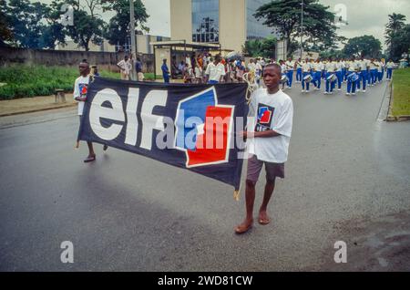 Ivory Coast, during a national holiday parade in Abidjan employees of French oil company ELF proudly march with the company flag. Stock Photo