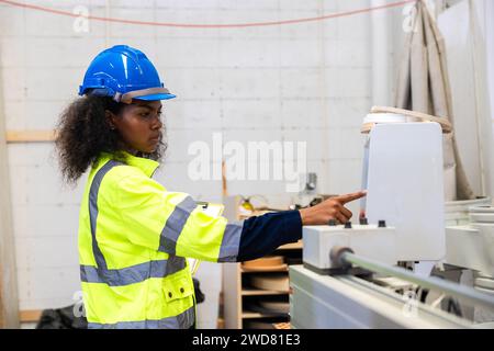 African black women worker work with wood cutter machine furniture factory industry with safety suit Stock Photo