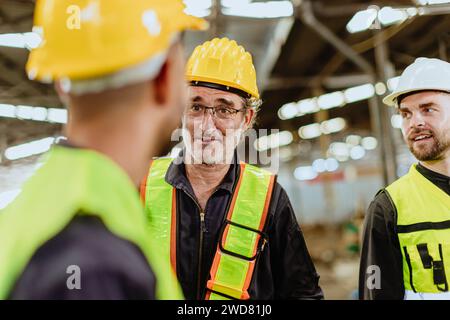senior professional engineer male worker happy talking with young man factory employee team in industry workplace. Stock Photo