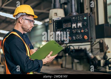 professional engineer working reading user manual control operate program CNC milling machine in heavy industry factory Stock Photo