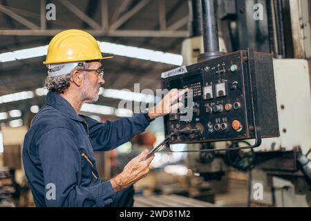senior professional engineer working control operate program CNC milling machine in heavy industry factory Stock Photo