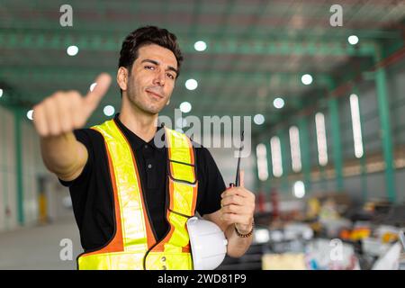 Engineer man hand like sign or factory worker wear safety helmet in warehouse site indoor Showing thumbs up happy smile.Good working finished job done Stock Photo