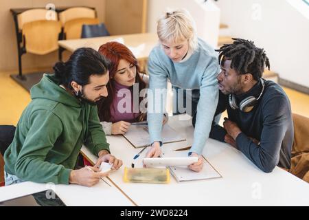Diverse group of students engaging in a focused group discussion over coursework, highlighting teamwork and academic cooperation in a modern education Stock Photo