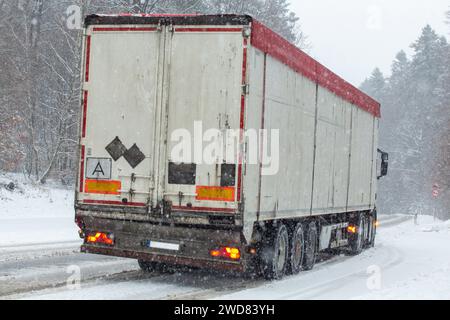 Lorry on snow-covered main road in the forest in driving snow Stock Photo