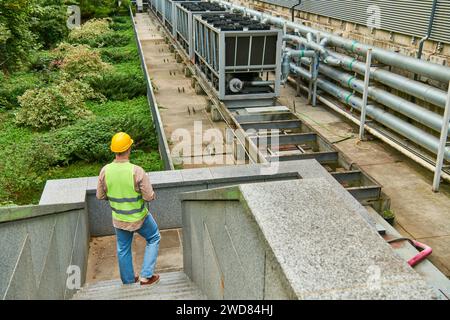 back view of dedicated professional in helmet and safety vest standing outside of data center Stock Photo