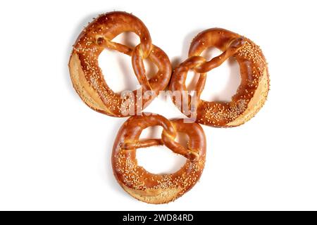 Three golden brown Bavarian pretzel top view with a generous amount of sesame seeds sprinkled over it is shown in this image. The pretzel has a knotte Stock Photo