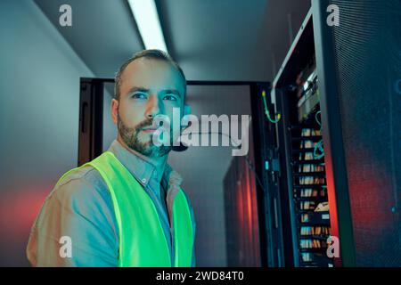 good looking specialist with beard in safety clothes inspecting data center and looking away Stock Photo