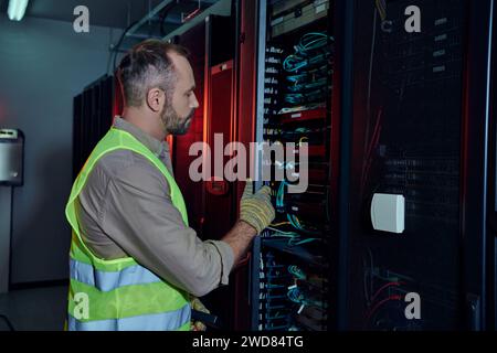 good looking professional in safety gloves and vest inspecting information storage, data center Stock Photo