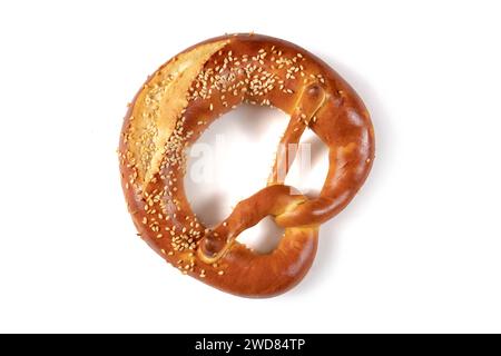 Golden brown Bavarian pretzel with a generous amount of sesame seeds sprinkled over it, from above on a white background. The pretzel's knotted shape Stock Photo