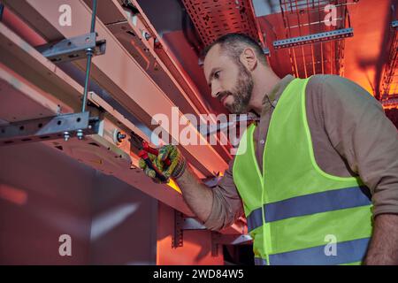 handsome focused professional in safety vest and gloves using pliers while working hard, data center Stock Photo