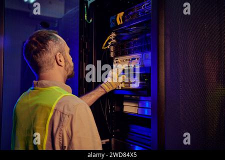 dedicated pensive technician in safety clothes inspecting information center, data storage Stock Photo