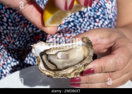 Eating of fresh live oysters at farm cafe in oyster-farming village, Arcachon bay, Cap Ferret peninsula, Bordeaux, France, close up Stock Photo