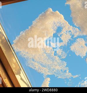 Close-up of intricate snowflake patterns on a window with the colorful sunset-illuminated blue sky in the background, creating a serene and picturesqu Stock Photo