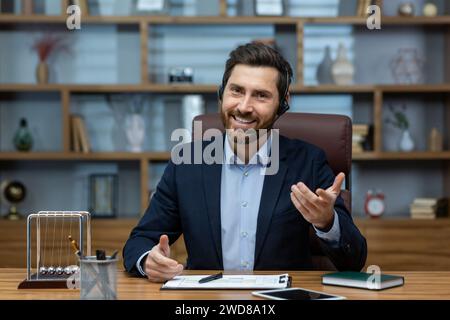 Experienced mature man in a suit and headset working from a well-organized home office, exuding confidence and charisma. Stock Photo