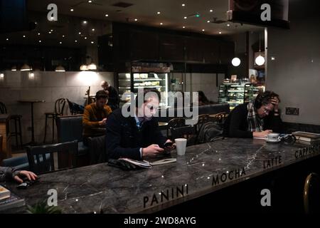 A london city worker sits alone listening to his headphones after a long days work in the financial district, England, United Kingdom Stock Photo