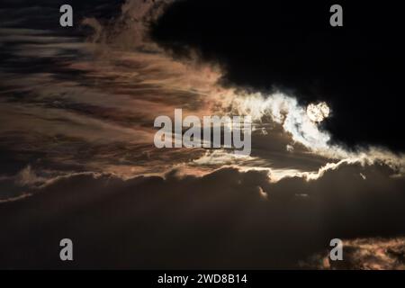The sun shines through dark clouds creating beams of light in the air. Stock Photo