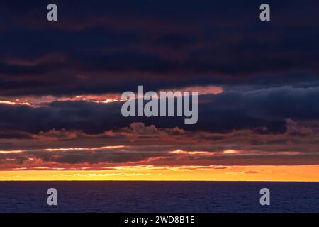 Colourful sunset over the sea with dramatic dark sky. Stock Photo
