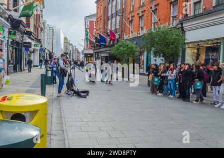 Dublin, Leinster, Ireland September 26 2023 - Busker entertaining shoppers listening in Grafton street pedestrian zone in Dublin city centre Stock Photo