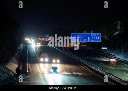 Nighttime traffic on german A3 highway between exits Bad Honnef and Neustadt with motion blur and large road signs during snowfall with large amount o Stock Photo