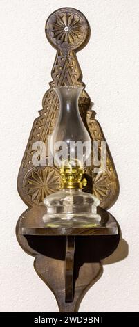Old oil lamp powered by kerosene hanging on the wall. Isolated white background Stock Photo
